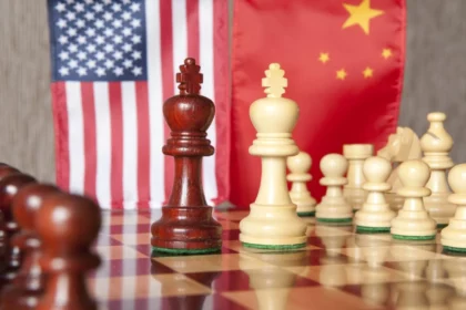 Chess pieces symbolizing U.S.–China strategic rivalry in front of American and Chinese flags.
